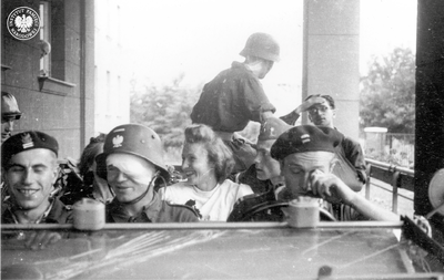 Powstanie Warszawskie na Mokotowie. Para młoda i grupa powstańców w zdobycznym niemieckim samochodzie Kübelwagen. na podjeździe przed Szpitalem Sióstr Elżbietanek przy ulicy Goszczyńskiego 1 (AIPN)