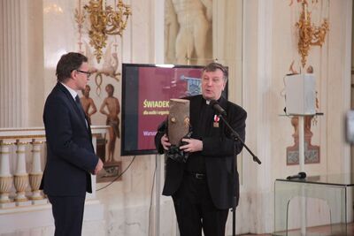 Ksiądz Pożarski podziękował za wyróżnienie, ofiarowując na ręce prezesa IPN część pnia świerka, który wyrósł na grobach ofiar reżimu stalinowskiego pochowanych na Cmentarzu w Lewaszowie w Petersburgu. Fot. Piotr Życieński (IPN)