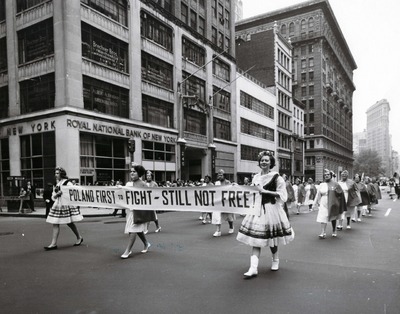 Kobiety z Korpusu Pomocniczego Pań przy Stowarzyszeniu Weteranów Armii Polskiej w Ameryce (SWAP) w Paradzie Pułaskiego przy 5 Alei na Manhattanie w Nowym Jorku, niosą baner z napisem po angielsku: „Poland first to fight – still not free” (Polska pierwsza w walce – wciąż nie jest wolna). Fot. z zasobu IPN, ze zbioru kopii cyfrowych fotografii przekazanych do IPN przez Stowarzyszenie Weteranów Armii Polskiej w Ameryce