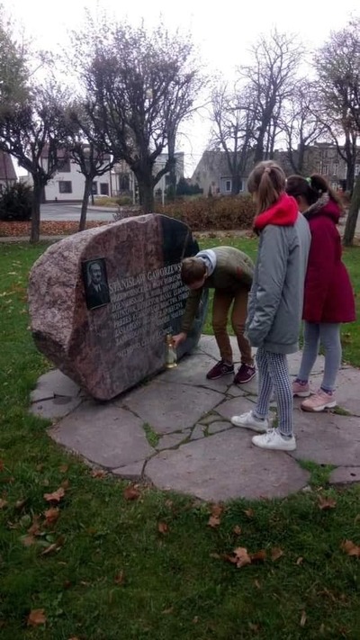 Uczniowie Szkoły Podstawowej w Witkowie zapalają znicz pod upamiętnieniem burmistrza Witkowa Stanisława Gaworzewskiego zamordowanego w KL Gusen