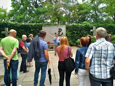 Przed tablicą pamięci w kwaterze Żołnierzy Polski Walczącej. Wakacyjny spacer z historią. Cmentarz Wojskowy na Powązkach – „Szlakiem Powstania Warszawskiego” – Warszawa, 10 sierpnia 2019