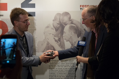 Sam Bryan pokazuje aparat fotograficzny, który jest taki sam jak ojca a zdjęciu